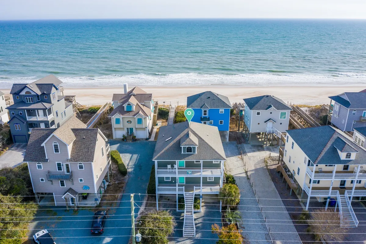 A sweeping view of the ocean with colorful beachfront properties lining the shore, suggesting both a vibrant local community and immediate beach access. The lively colors and proximity to the water evoke a sense of adventure and the possibility to partake in a range of coastal activities.