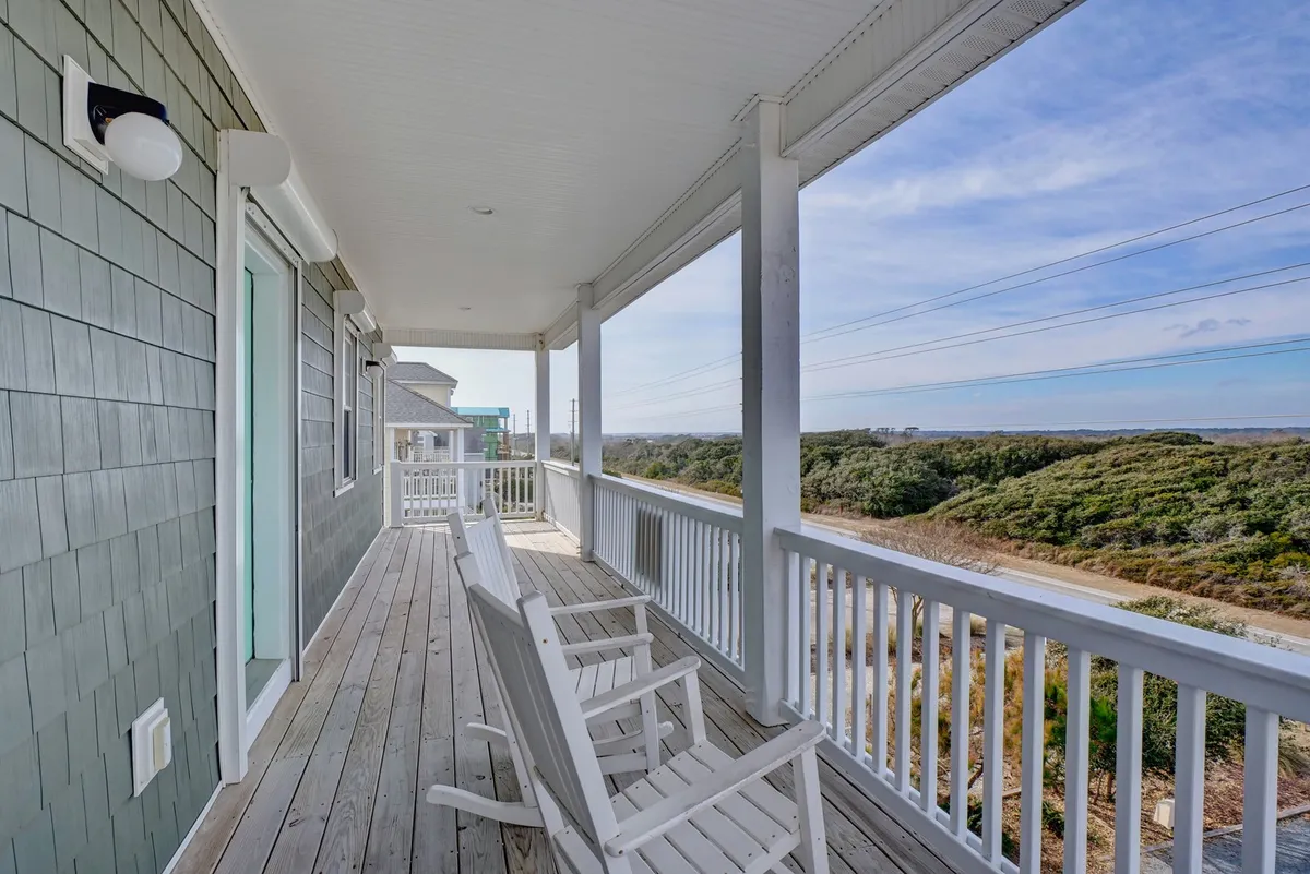 A serene exterior scene featuring rocking chairs on a porch overlooking the landscape. The view gives a sense of tranquility and a perfect spot to relax after a day of exploring, while still connecting the home to the beauty of the surrounding region.
