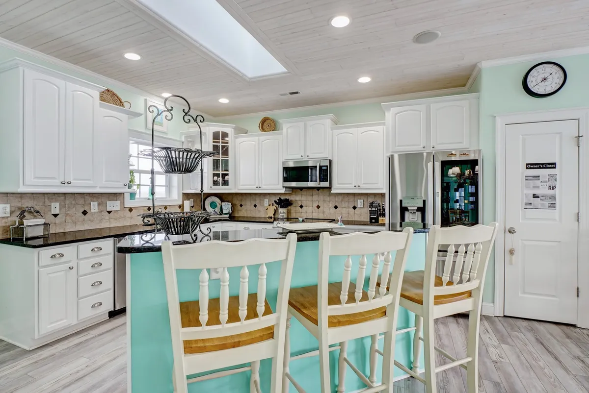A stylish kitchen with a central island and bar stools, white cabinets, and black countertops. The space is designed for both cooking and socializing, inviting guests to gather around during meal prep or enjoy casual conversation.